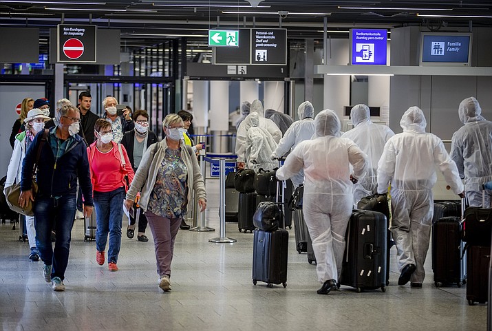 Passengers, left, who just arrived at the airport walk past crew members of South African Airways, right, on their way to the security check at the airport in Frankfurt, Germany, Saturday, April 18, 2020. Due to the new coronavirus outbreak about 95 percent of the flights were cancelled. (Michael Probst/AP)