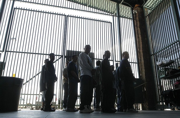 In this Thursday Aug. 9, 2012, file photo, persons are detained for being in the country illegally and are moved out of the holding area after being processed at the Tucson Sector of the U.S. Border Patrol's headquarters in Tucson, Ariz. The federal government is appealing an order by a U.S. District Court judge requiring the Border Patrol to provide beds, blankets, showers and medical evaluations to migrants held in its Tucson Sector facilities for over 48 hours. (AP Photo/Ross D. Franklin, File)