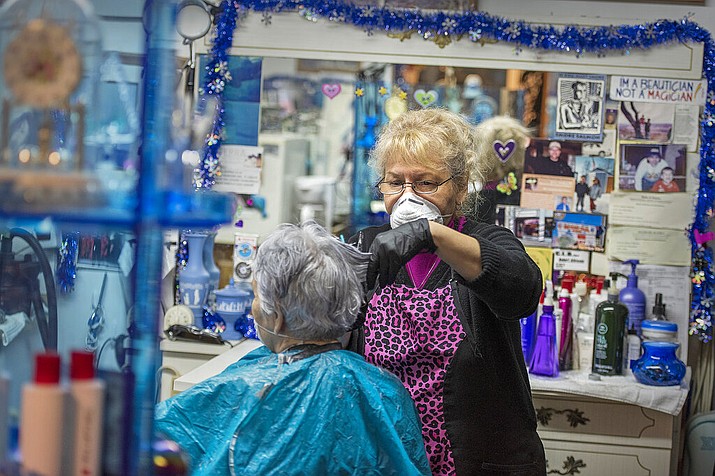Dody's Hair Creation owner and operator Dody Morrison wears personal protective equipment during a haircut service for Evelyn Wilson, Friday, April 24, 2020, at her salon in Ketchikan, Alaska. Both Wilson and Morrison conversed with each other from behind masks. (Dustin Safranek/Ketchikan Daily News via AP)