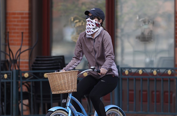 A bicyclist wears face protection against the new coronavirus while pedaling through Larimer Square early Saturday, April 25, 2020, in downtown Denver. (David Zalubowski/AP)