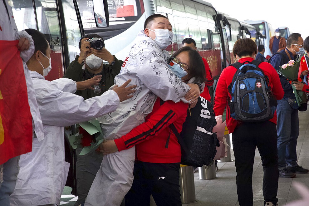 A medical worker from China's Jilin Province, in red, embraces a colleague from Wuhan as she prepares to return home at Wuhan Tianhe International Airport in Wuhan in central China's Hubei Province, April 8, 2020. Within hours of China lifting an 11-week lockdown on the central city of Wuhan, tens of thousands people had left the city by train and plane alone, according to local media reports. (AP Photo/Ng Han Guan)
