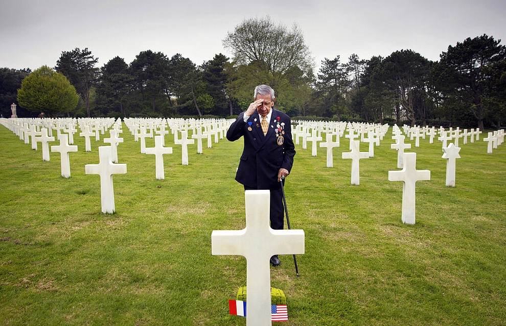 In this May 1, 2019 file photo, World War II and D-Day veteran Charles Norman Shay, from Indian Island, Maine, salutes the grave of fellow soldier Edward Morozewicz at the Normandy American Cemetery in Colleville-sur-Mer, Normandy, France. Instead of parades, remembrances, embraces and one last great hurrah for veteran soldiers who are mostly in their nineties to celebrate VE Day, it is instead a lockdown due to the coronavirus, COVID-19. (AP Photo/Virginia Mayo, File)
