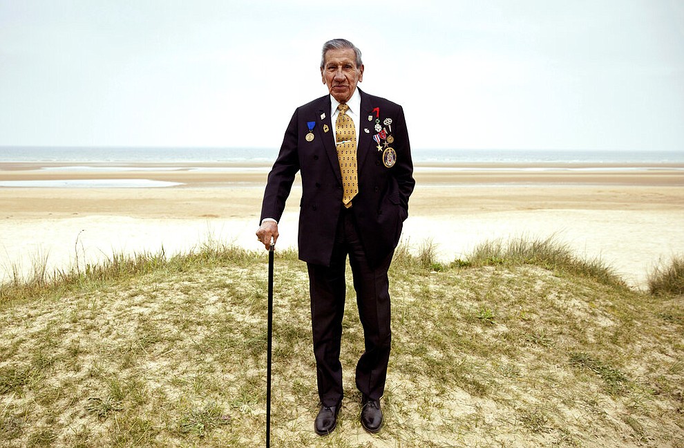 In this Wednesday, May 1, 2019 file photo, World War II and D-Day veteran Charles Norman Shay, from Maine, poses at the Charles Shay monument on Omaha Beach in Normandy, France. Instead of parades, remembrances, embraces and one last great hurrah for veteran soldiers who are mostly in their nineties to celebrate VE Day, it is instead a lockdown due to the coronavirus, COVID-19. (AP Photo/Virginia Mayo, File)
