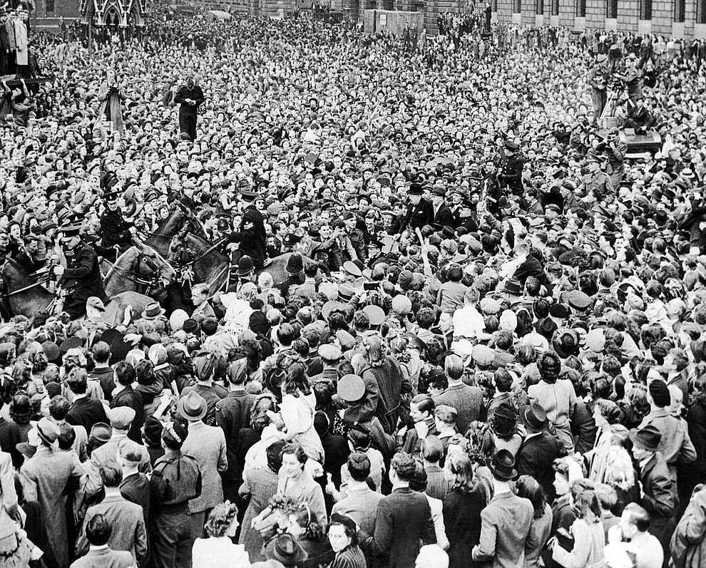 FILE - In this May 8, 1945 file photo mounted policemen strive to clear a path for Prime Minister Winston Churchill, center, in his car on its way through a surging crowd of VE Day celebrants in Parliament Square, London after the announcement of Germany's surrender in World War II. On Friday's 75th anniversary of the end of World War II in Europe, talk of war is afoot again — this time against a disease that has killed at least a quarter of a million people worldwide. Instead of parades, remembrances and one last great hurrah for veterans now mostly in their nineties, it is a time of lockdown and loneliness, with memories bitter and sweet (AP Photo, File)