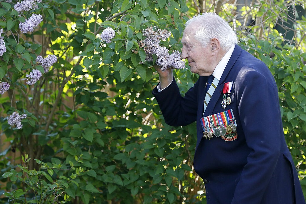 World War II Veteran Mervyn Kersh smells one of the plants in his garden in London, Monday, May 4, 2020. On Friday's 75th anniversary of the end of World War II in Europe, talk of war is afoot again — this time against a disease that has killed at least a quarter of a million people worldwide. Instead of parades, remembrances and one last great hurrah for veterans now mostly in their nineties, it is a time of lockdown and loneliness, with memories bitter and sweet (AP Photo/Frank Augstein)