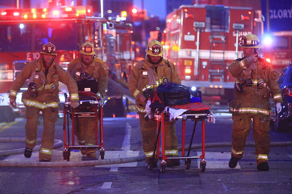 Los Angeles Fire Department firefighters push ambulance cots at the scene of a structure fire that injured multiple firefighters, according to a fire department spokesman, Saturday, May 16, 2020, in Los Angeles. (AP Photo/Damian Dovarganes)