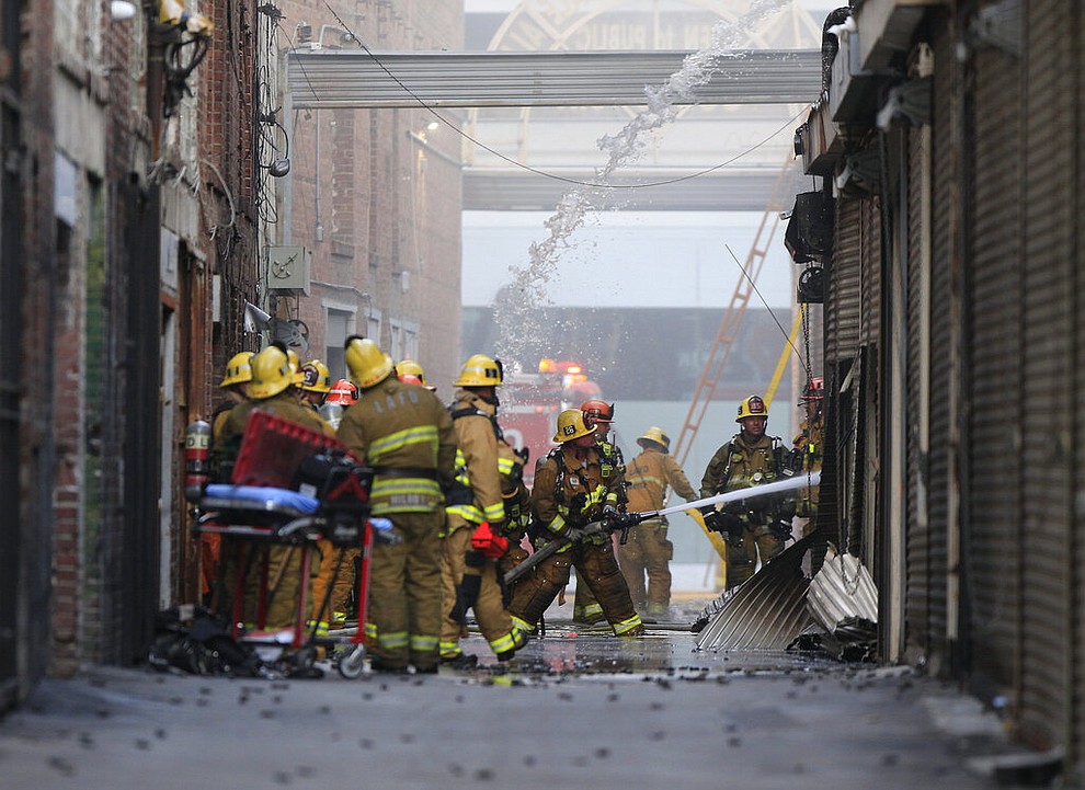Los Angeles Fire Department firefighters work the scene of a structure fire that injured multiple firefighters, according to a fire department spokesman, Saturday, May 16, 2020, in Los Angeles. (AP Photo/Damian Dovarganes)