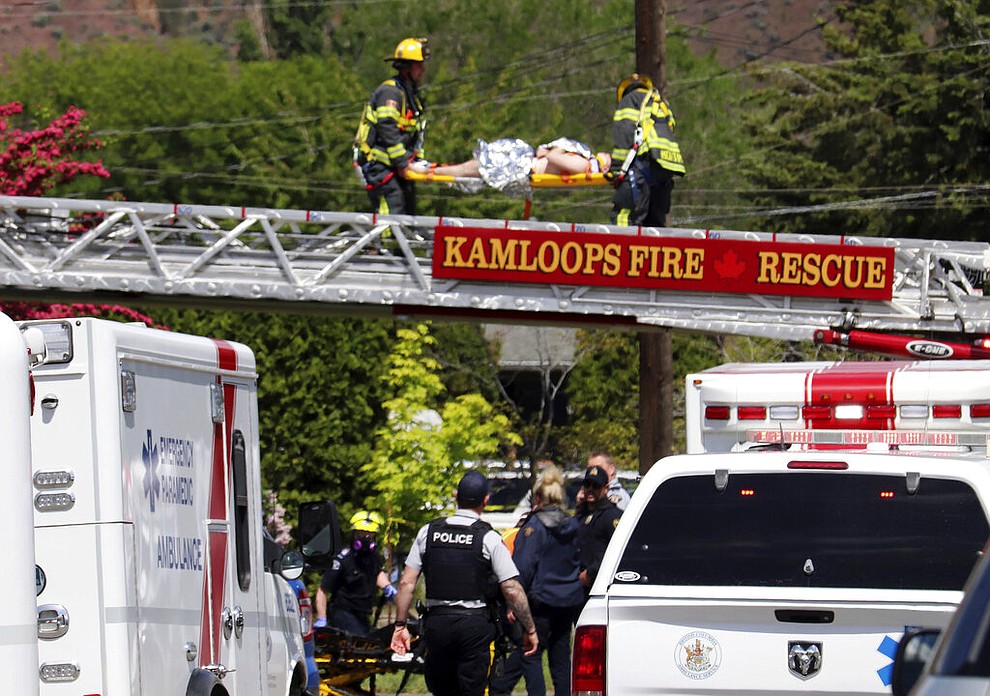 First responders carry an injured person on a stretcher across a fire truck ladder from a rooftop at the scene of a crash involving a Canadian Forces Snowbirds airplane in Kamloops, British Columbia, Sunday, May 17, 2020. (Brendan Kergin/Castanet Kamloops/The Canadian Press via AP)