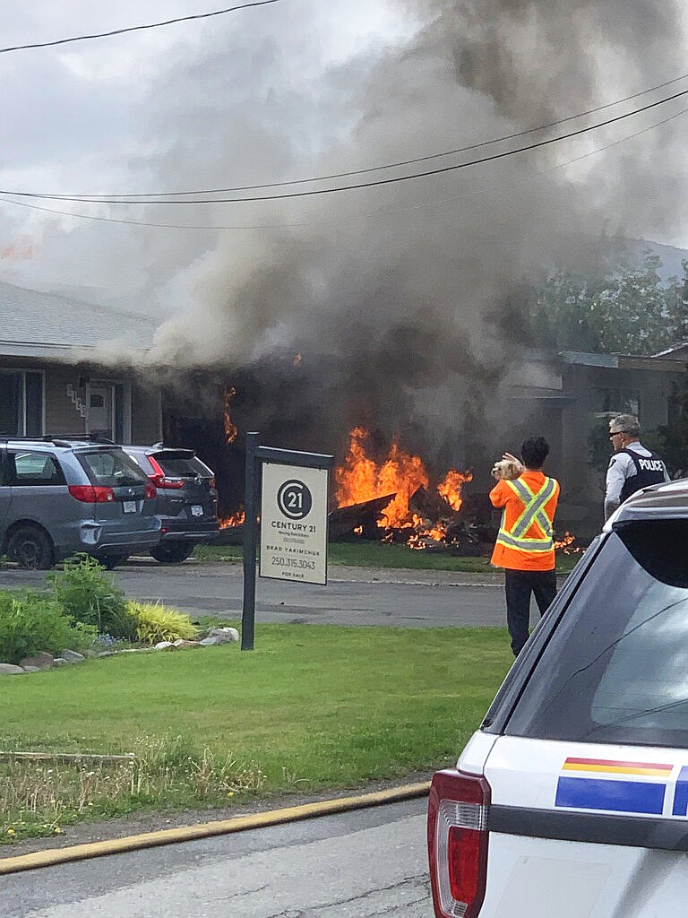 This photo provided by Elwood Delaney shows the scene of a crash involving a Canadian Forces Snowbirds airplane in Kamloops, Canada, Sunday, May 17, 2020. A Canadian acrobatic jet has crashed into the British Columbia neighborhood during a flyover intended to boost morale during the pandemic, killing at least one crew member and setting the house on fire. (Elwood Delaney via AP)