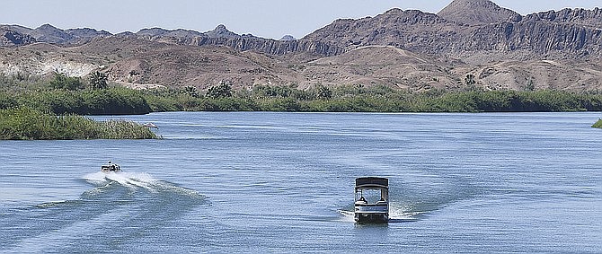 A boat heads down the Colorado River while another heads upriver May 21, 2020. A Phoenix-based company that was eyeing the Little Colorado River for power generation is floating a new proposal that would rely on groundwater rather than surface water to make electricity. (Randy Hoeft/The Yuma Sun via AP)