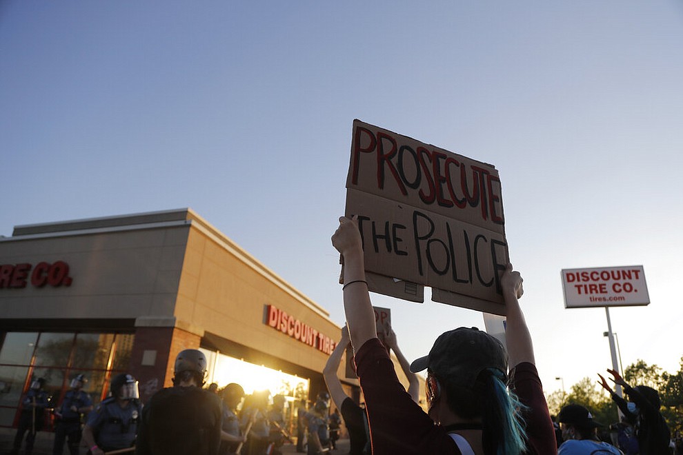 Demonstrators gather in front of a tire store Thursday, May 28, 2020, in St. Paul, Minn. Protests over the death of George Floyd, a handcuffed black man who died in police custody, broke out for a third straight night. (AP Photo/Julio Cortez)