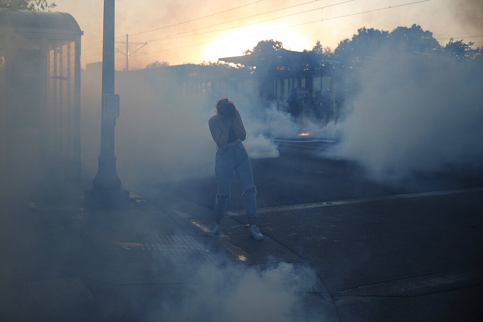 A woman is surrounded by teargas Thursday, May 28, 2020, in St. Paul, Minn. Protests over the death of George Floyd, the black man who died in police custody, broke out in Minneapolis for a third straight night. (AP Photo/John Minchillo)