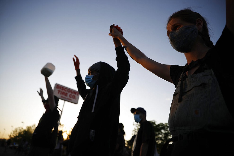 Demonstrators join hands Thursday, May 28, 2020, in St. Paul, Minn. Protests over the death of George Floyd, a black man who died in police custody, broke out in Minneapolis for a third straight night. (AP Photo/John Minchillo)