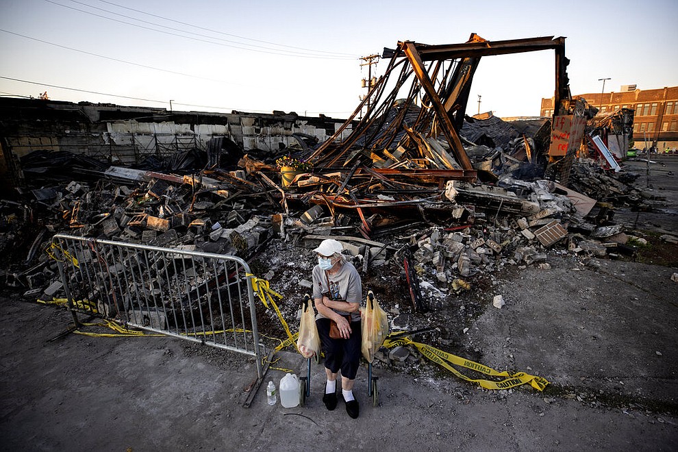 Sandra King, 70, waits for her granddaughter near the remains of AutoZone across from the Minneapolis 3rd Police Precinct in  in Minneapolis on Thursday, May 28, 2020. King, who lives in the neighborhood was brought to a protest by her granddaughter. (Carlos Gonzalez/Star Tribune via AP)