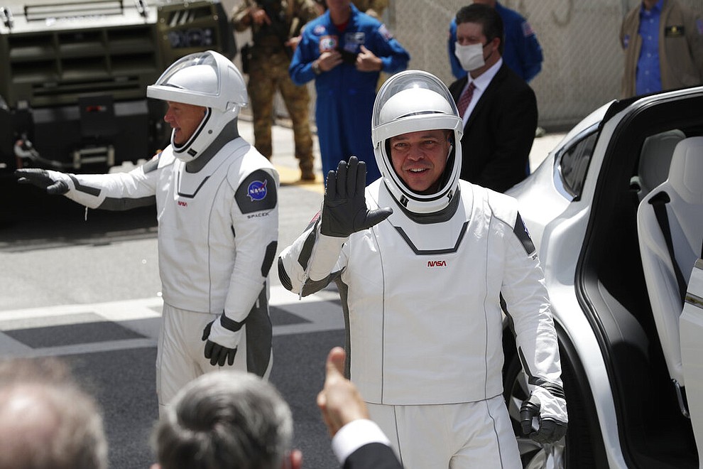 NASA astronauts Douglas Hurley, left, and Robert Behnken wave as they exit the Neil A. Armstrong Operations and Checkout Building on their way to Pad 39-A, at the Kennedy Space Center in Cape Canaveral, Fla., Saturday, May 30, 2020. The two astronauts will fly on a SpaceX test flight to the International Space Station. For the first time in nearly a decade, astronauts will blast into orbit aboard an American rocket from American soil, a first for a private company. (AP Photo/John Raoux)