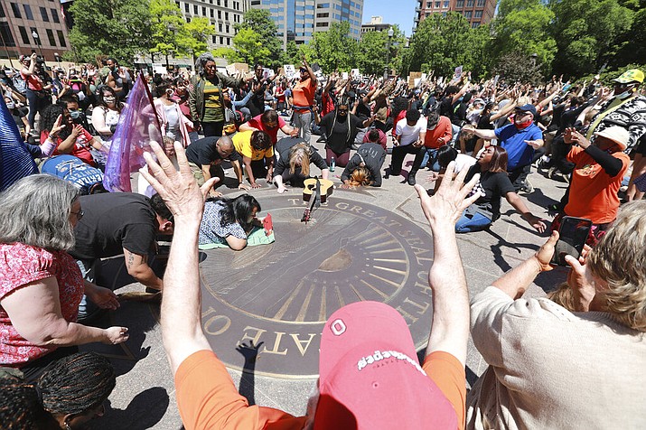 Members of the Shiloh Christian Center pray, sing and speak in tounges on the "With God All Things Are Possible" seal on the west lawn of the Ohio Statehouse as protesters gather at the Ohio Statehouse for a peaceful Sunday, May 31, 2020 protest over the death of George Floyd, a black man who was killed in police custody in Minneapolis on May 25. (Doral Chenoweth/The Columbus Dispatch via AP)