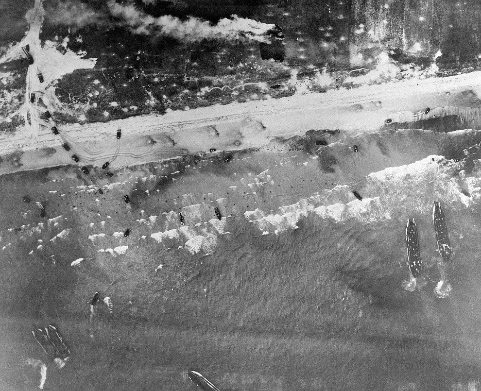 Men and assault vehicles storm the Normandy Beach of France, as allied landing craft arrive at their destination on D-Day, June 6, 1944. Note men coming ashore in surf and vehicles starting inland. (AP Photo)..