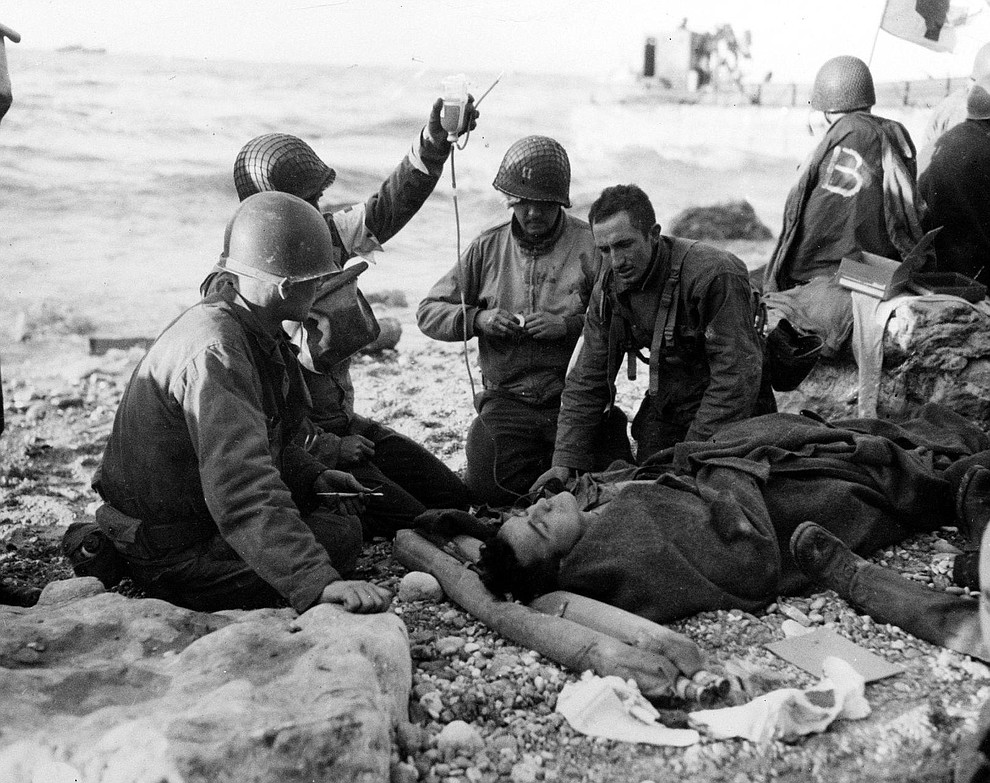 U.S. Army medical personnel administer a plasma transfusion to a wounded comrade, who survived when his landing craft went down off the coast of Normandy, France, in the early days of the Allied landing operations in June 1944. (AP Photo)..