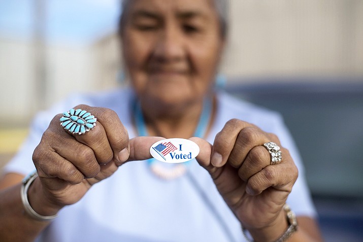 Mildred James of Sanders, Arizona, shows off her "I Voted" sticker as she waits for results of the Navajo Nation presidential primary election to be revealed in Window Rock, Ariz. In race for Navajo Nation president, candidates have similar priorities. Their leadership style might be the deciding factor. The contenders are Joe Shirley Jr., and Jonathan Nez. (AP Photo/Cayla Nimmo, File)