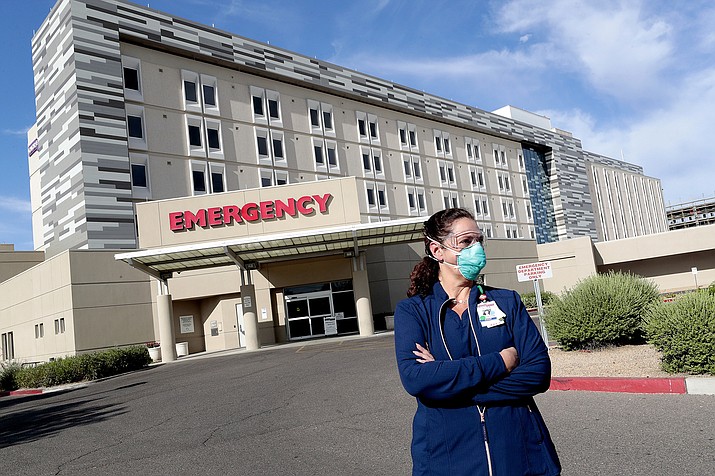 Caroline Maloney stands outside HonorHealth's Scottsdale Osborn Medical Center at the end of her overnight shift early Friday, June 26, 2020 in Scottsdale, Ariz. Arizona nurses and doctors find themselves on the frontline as the coronavirus rips through the state, making it one of the world's hot spots. (AP Photo/Matt York)