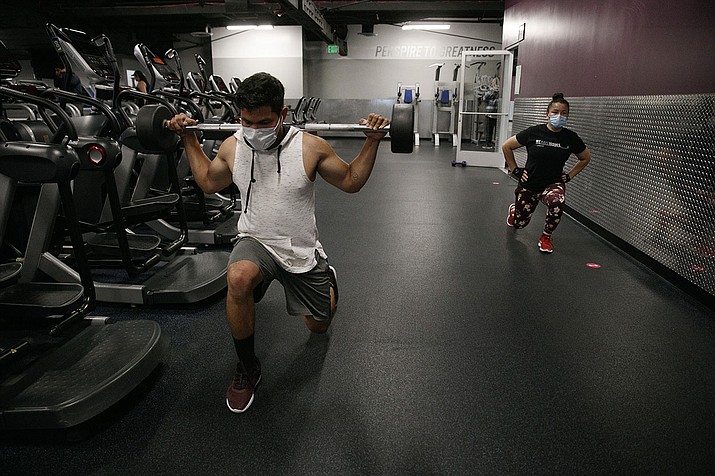 In this Friday, June 26, 2020 file photo, people wear masks while exercising at a gym in Los Angeles. On Thursday, July 9, 2020, the World Health Organization is acknowledging the possibility that COVID-19 might be spread in the air under certain conditions — after more than 200 scientists urged the agency to do so. (Jae C. Hong/AP)