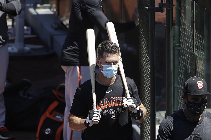 In this Sunday, July 5, 2020, file photo, San Francisco Giants' Buster Posey carries his bats during a baseball practice in San Francisco. Posey is the latest big-name player to skip this season because of concerns over the coronavirus pandemic. Posey announced his decision on Friday, July 10, 2020. He says his family finalized the adoption of identical twin girls this week. The babies were born prematurely and Posey said after consultations with his wife and doctor he decided to opt out of the season. (AP Photo/Jeff Chiu, File)