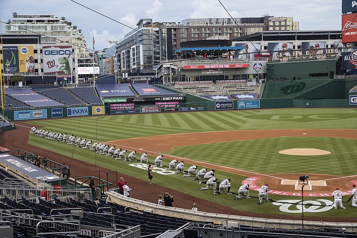 Members of the New York Yankees and Washington Nationals kneel and hold a piece of black fabric before an opening day baseball game at Nationals Park, Thursday, July 23, 2020, in Washington. (Alex Brandon/AP)