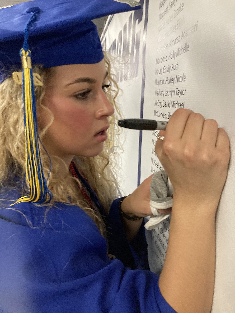 Prescott High School graduate Shannon McCracken writes her name on a graduate poster in the PDS lobby at the school's graduation Saturday, Aug. 8, 2020. (Nanci Hutson/Courier)