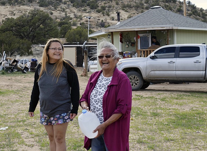This photo taken April 24, 2020, shows Wynice Franklin, left, and her mother Louise Johnson, right, receiving bottled water from local officials in Church Rock, N.M. Johnson said her biggest challenge during the coronavirus pandemic is getting water to her home. (Vida Volkert,/Gallup Independent via AP)