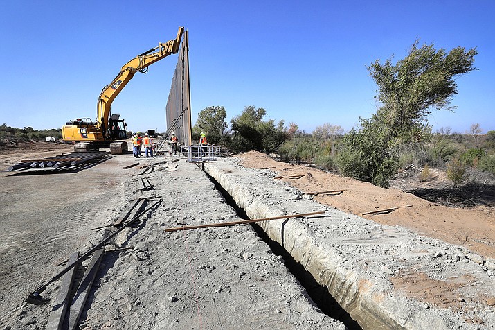 In this Sept. 10, 2019, file photo government contractors erect a section of Pentagon-funded border wall along the Colorado River, in Yuma, Arizona. (AP Photo/Matt York, File)
