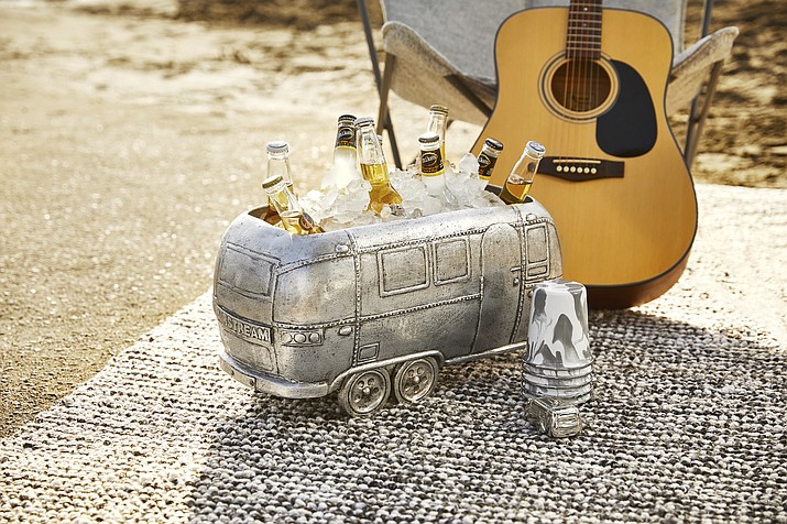 In a new collaboration with the RV company Airstream, Pottery Barn has launched a collection of gear that includes a fun drinks cooler shaped like the iconic trailer, shown here, as well as logo-embroidered napery and tumblers, bowls and plates in a snazzy grey and white enamelware swirl pattern. (Pottery Barn via AP)