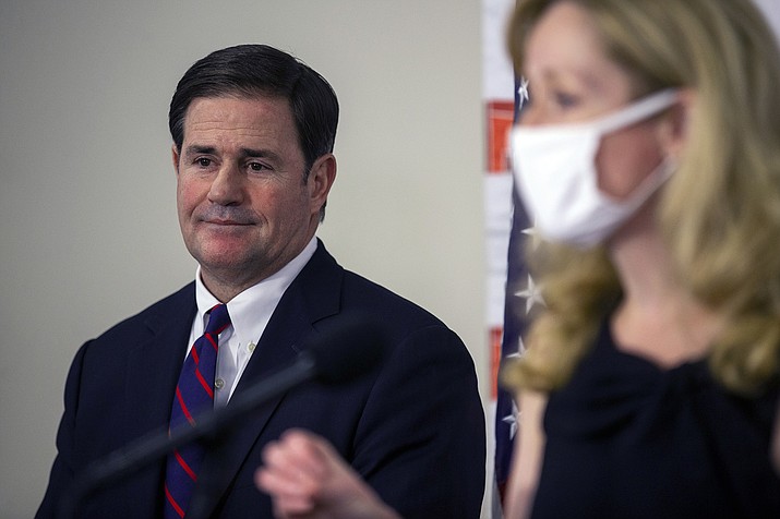 Gov. Doug Ducey listens as Arizona Department of Health Services Director Cara Christ speaks during a press conference regarding the COVID-19 pandemic, Thursday, Aug. 13, 2020, at the Arizona Department of Health Services in Phoenix. (Sean Logan/The Arizona Republic via AP)