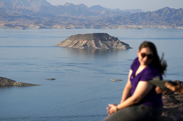 People sit on an overlook on Lake Mead at the Lake Mead National Recreation Area, Thursday, Aug. 13, 2020, near Boulder City, Nev. The U.S. Bureau of Reclamation is expected to release projections that suggest the levels in Lake Powell and Lake Mead dipped slightly compared with last year. (AP Photo/John Locher)
