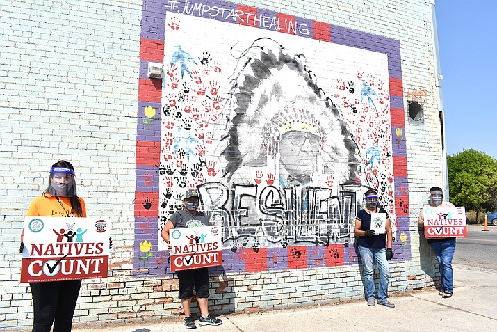 Activists hold signs promoting Native American participation in the U.S. census in front of a mural of Crow Tribe historian and Presidential Medal of Freedom recipient Joe Medicine Crow on the Crow Indian Reservation in Lodge Grass, Montana on Aug. 26, 2020. The activists for Western Native Voice say participation in the census is key to making sure the tribe gets sufficient federal money for schools, housing and other needs. (AP Photo/Matthew Brown)