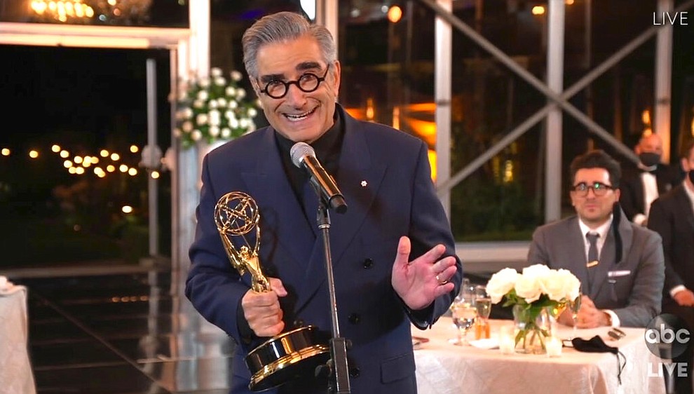In this video grab captured on Sept. 20, 2020, courtesy of the Academy of Television Arts & Sciences and ABC Entertainment, Eugene Levy accepts the outstanding lead actor in a comedy series award for "Schitt's Creek" as his son and castmate Dan Levy looks on at right during the 72nd Emmy Awards broadcast. (The Television Academy and ABC Entertainment via AP)