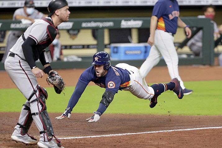 Houston Astros George Springer, right, dives for home plate on his inside the park home run as Arizona Diamondbacks catcher Carson Kelly, left, waits for the ball during the sixth inning of a baseball game Sunday, Sept. 20, 2020, in Houston. (AP Photo/Michael Wyke)
