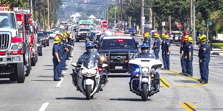 The California Highway Patrol leads the procession along with U.S. Forest Service vehicles as they escort fallen firefighter Charles Morton, killed while battling a blaze in the mountains east of Los Angeles, along Hewes Street in Orange, California, Sept. 22, 2020, from San Bernardino to the Ferrara Colonial Mortuary in Orange. (Mark Rightmire/The Orange County Register via AP)