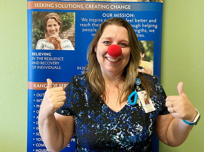 Southwest Behavioral & Health Services Program Director and certified laughter therapy professional counselor, Christine Hayes, standing next to her agency’s sign in the front hallway – complete with her bright red clown nose. (Nanci Hutson/Courier)