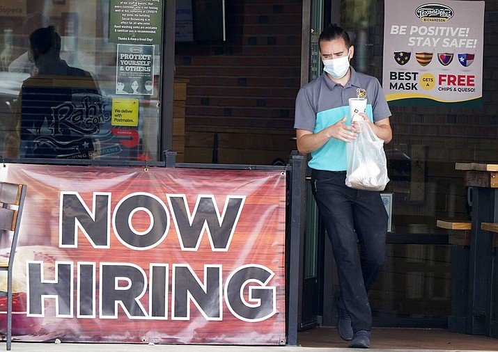 In this Sept. 2, 2020 file photo, a customer wears a face mask as they carry their order past a now hiring sign at an eatery in Richardson, Texas. The number of Americans seeking unemployment benefits fell last week to 751,000, the lowest since March, but it's still historically high and indicates the viral pandemic is still forcing many employers to cut jobs. (AP Photo/LM Otero, File)