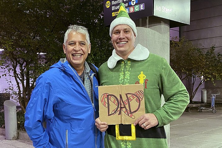 Doug Henning, right, who was adopted as a baby, poses with his biological father after meeting face to face for the first time on Tuesday, Nov. 24, 2020, at Logan International Airport in Boston. Henning, of Eliot, Maine, wore a costume like the one actor Will Ferrell's character wore in the movie "Elf" and he broke into the same awkward song from the movie while meeting his father. (Rebecca Taylor Henning via AP)
