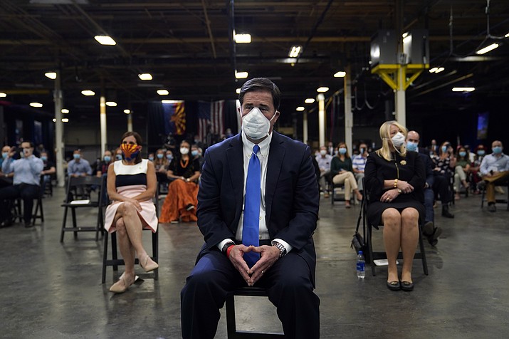 In this May 5, 2020 photo, Gov. Doug Ducey waits to hear President Donald Trump speak after a tour of a Honeywell International plant that manufactures personal protective equipment in Phoenix. At right is Rep. Debbie Lesko, R-Ariz. From March 30 through April 28, Arizona health officials bought more than $59 million worth of masks, gowns, gloves and other personal protective equipment to protect hospital workers and others on the frontlines of the coronavirus pandemic. (Evan Vucci/AP, File)