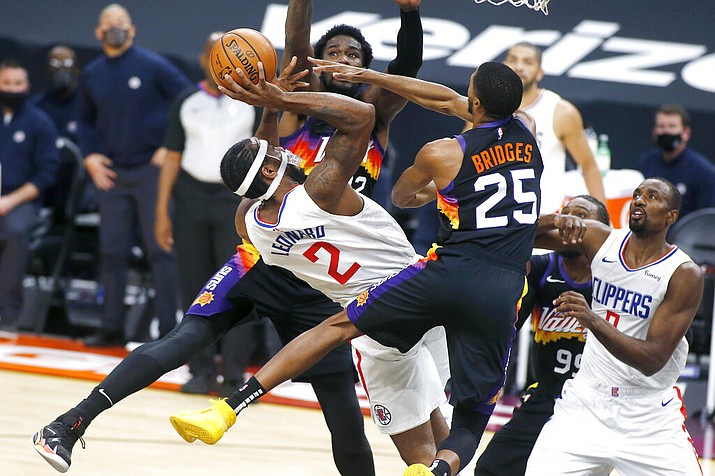 Los Angeles Clippers forward Kawhi Leonard (2) shoots over the defense of Phoenix Suns forward Mikal Bridges (25) and center Deandre Ayton (22) during the first half of an NBA basketball game Sunday, Jan. 3, 2021, in Phoenix. (AP Photo/Ralph Freso)