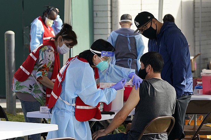 In this Jan. 13, 2021, file photo, health care workers receive a COVID-19 vaccination at Ritchie Valens Recreation Center, Wednesday, Jan. 13, 2021, in Pacoima, Calif. The rapid expansion of vaccinations to senior citizens across the U.S. has led to bottlenecks, system crashes and hard feelings in many states because of overwhelming demand for the shots. (Marcio Jose Sanchez, AP File)