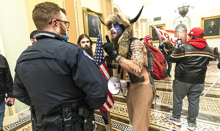 In this Jan. 6, 2021, file photo supporters of President Donald Trump are confronted by U.S. Capitol Police officers outside the Senate Chamber inside the Capitol in Washington. An Arizona man seen in photos and video of the mob wearing a fur hat with horns was also charged Saturday in Wednesday's chaos. Jacob Anthony Chansley, who also goes by the name Jake Angeli, was taken into custody Saturday, Jan. 9. (AP Photo/Manuel Balce Ceneta, File)