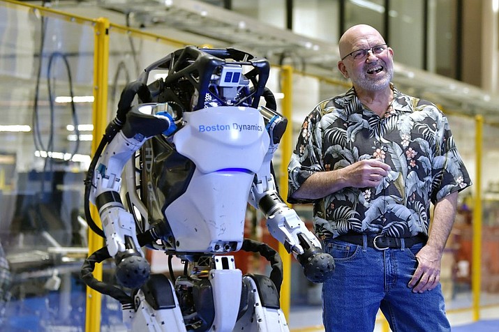 Marc Raibert, founder and chair of Boston Dynamics stands beside one of the company's Atlas robots during an interview and demonstration, Wednesday, Jan. 13, 2021, at their facilities in Waltham, Mass. The company engineered the robot to be able to dance in a fluid manner that is almost human. (AP Photo/Josh Reynolds)
