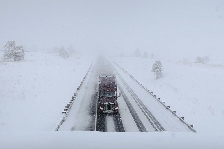 A semi-truck travels on Interstate 40 in Bellemont, Ariz. Monday, Jan. 25, 2021. A series of winter storms have dropped more precipitation in Flagstaff than the city had during last summer's monsoon season. The recent snow measured as water topped the amount of rain that fell from mid-June through September, the driest monsoon season on record. (Felicia Fonseca/AP)