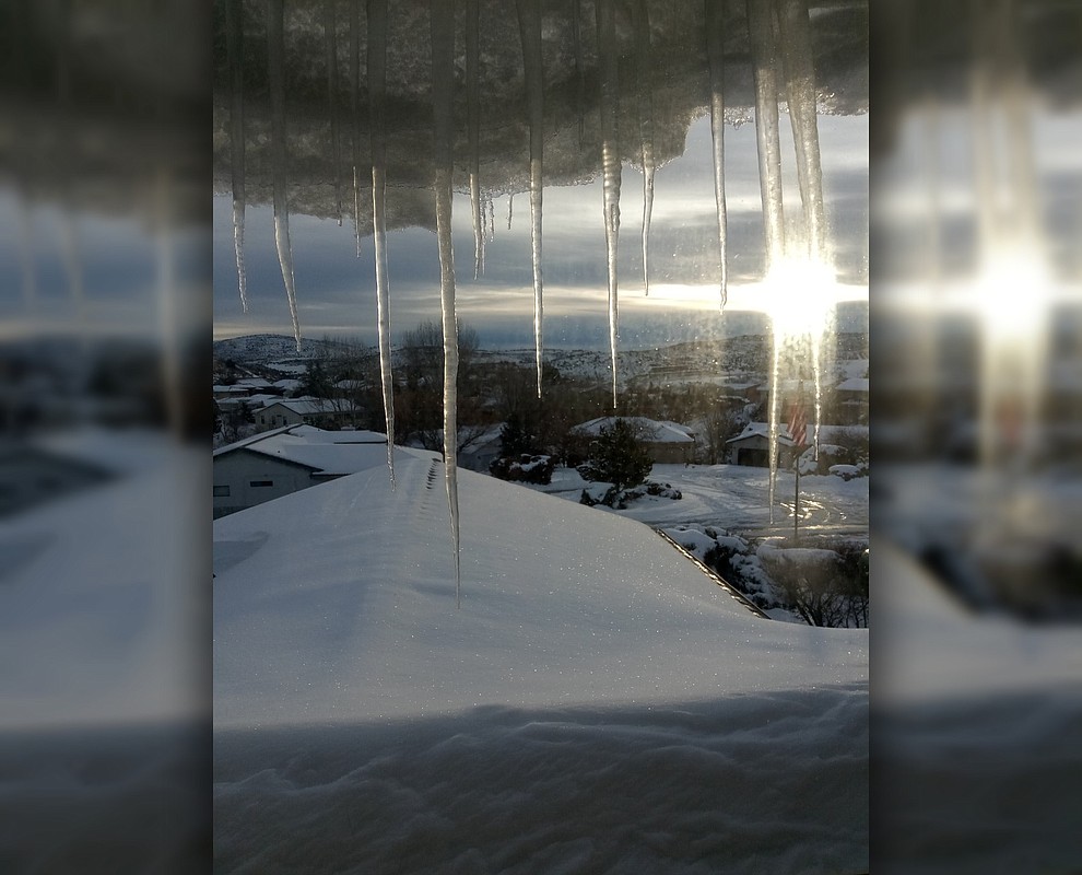 "I find this picture interesting because our American Flag is sitting under the Shining sun and between two icicles." Photo submitted by Susan Gest.