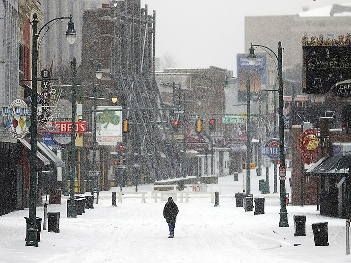 A lone man walks down the center of a snowy Beale Street in Downtown Memphis, Tenn., Wednesday, Feb. 17, 2021. (Jim Weber/Daily Memphian via AP)