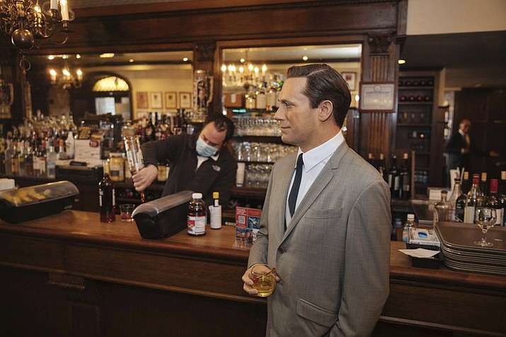 A wax statue of actor Jon Hamm stands by the bar with a drink at Peter Luger Steak House on Friday, Feb, 26, 2021, in New York. The statue, on loan from Madame Tussauds, will help fill out the restaurant during COVID-19 occupancy restrictions. (AP Photo/Kevin Hagen)