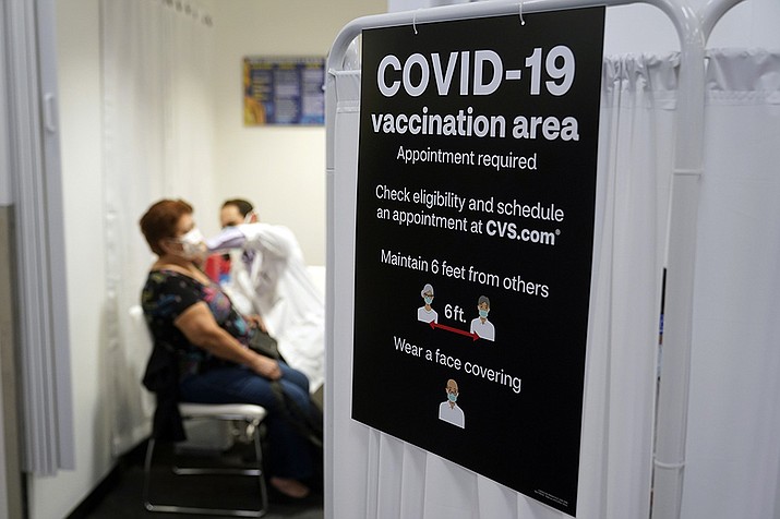 In this March 1, 2021, file photo, a patient receives a shot of the Moderna COVID-19 vaccine next to a guidelines sign at a CVS Pharmacy branch in Los Angeles. More than 27 million Americans fully vaccinated against the coronavirus will have to keep waiting for guidance from U.S. health officials for what they should and shouldn’t do. The Biden administration said Friday, March 5, it’s focused on getting the guidance right and accommodating emerging science. (Marcio Jose Sanchez, AP File)